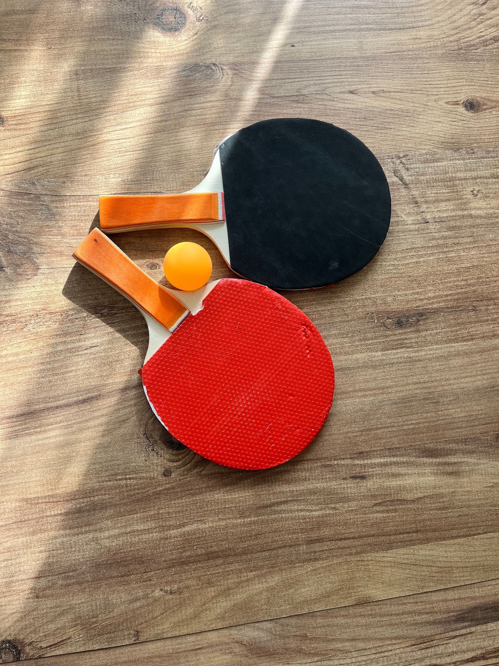 Deux raquettes et une balle posées sur un parquet